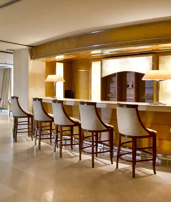 Bar con sillas altas y l&aacute;mparas iluminando el mostrador.