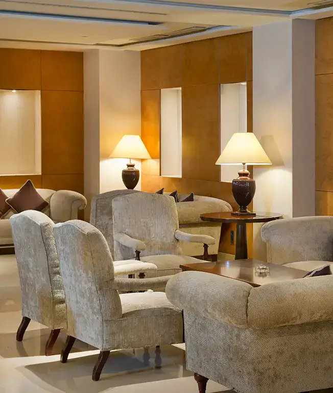 Sala elegante con sillones, mesas y l&aacute;mparas de mesa encendidas.