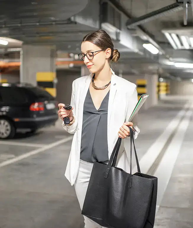 Mujer con bolso y llaves en un estacionamiento subterr&aacute;neo.