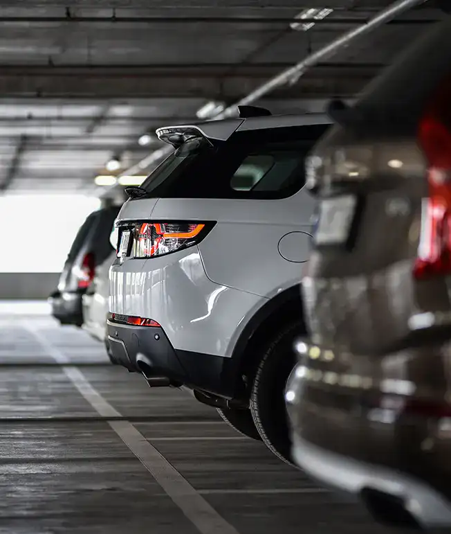 Coches estacionados en fila dentro de un aparcamiento cubierto.