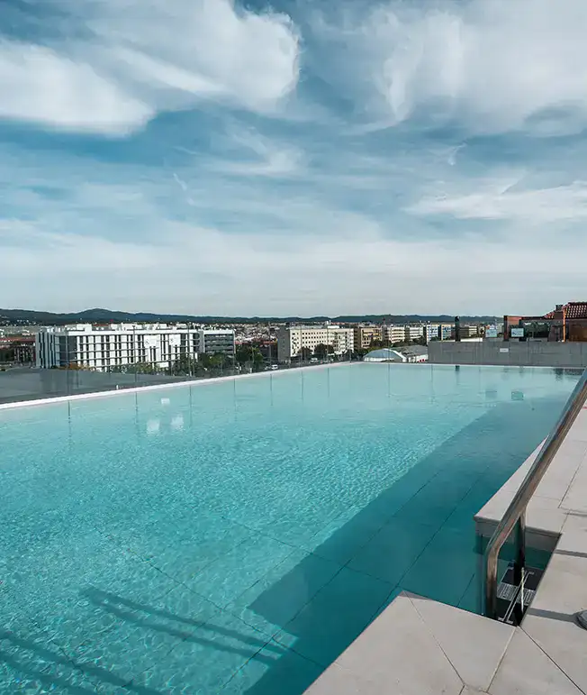 Piscina infinita con vista a la ciudad y cielo nublado.