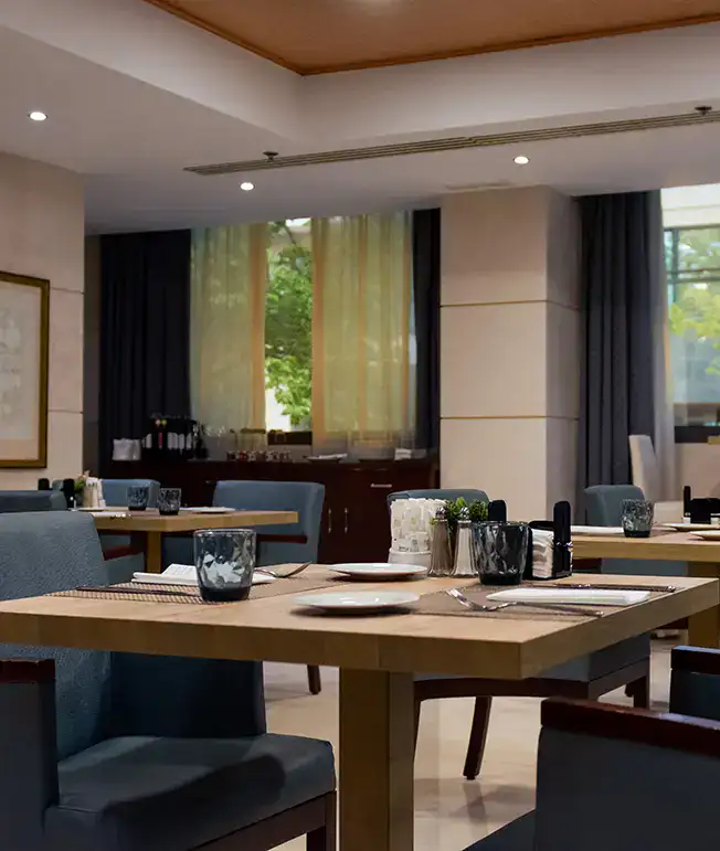 Restaurante elegante con mesas vac&iacute;as y cubiertos ordenados.