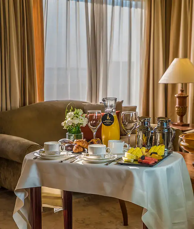 Mesa con desayuno de hotel, incluye caf&eacute;, jugo, fruta y pasteles.