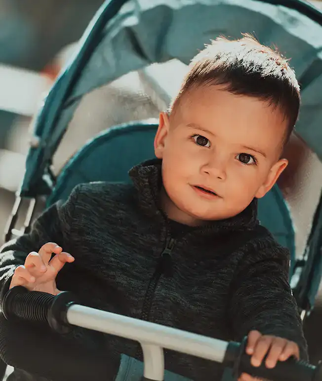 Un ni&ntilde;o en un cochecito mirando a la c&aacute;mara.