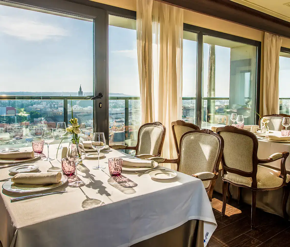 Mesa elegante con vista panor&aacute;mica de la ciudad a trav&eacute;s de grandes ventanales.