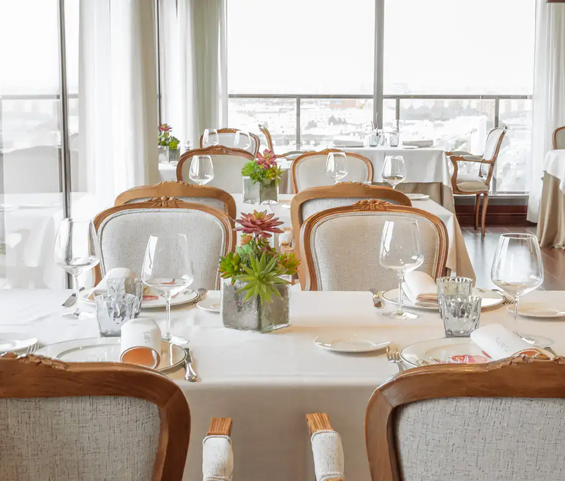 Restaurante elegante, mesas con manteles blancos y copas listas para servir.