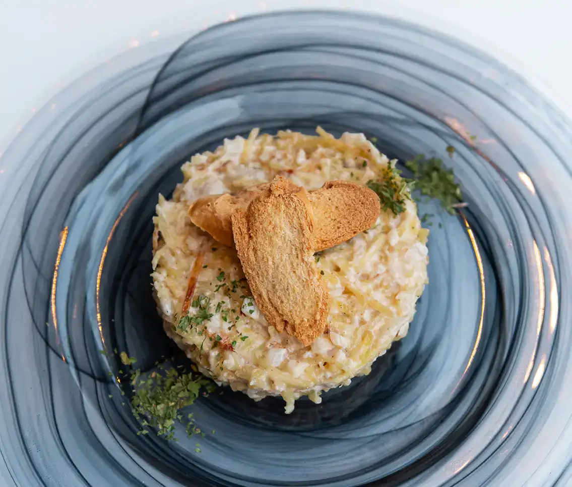 Ensalada de cangrejo con tostadas sobre plato decorativo azul.