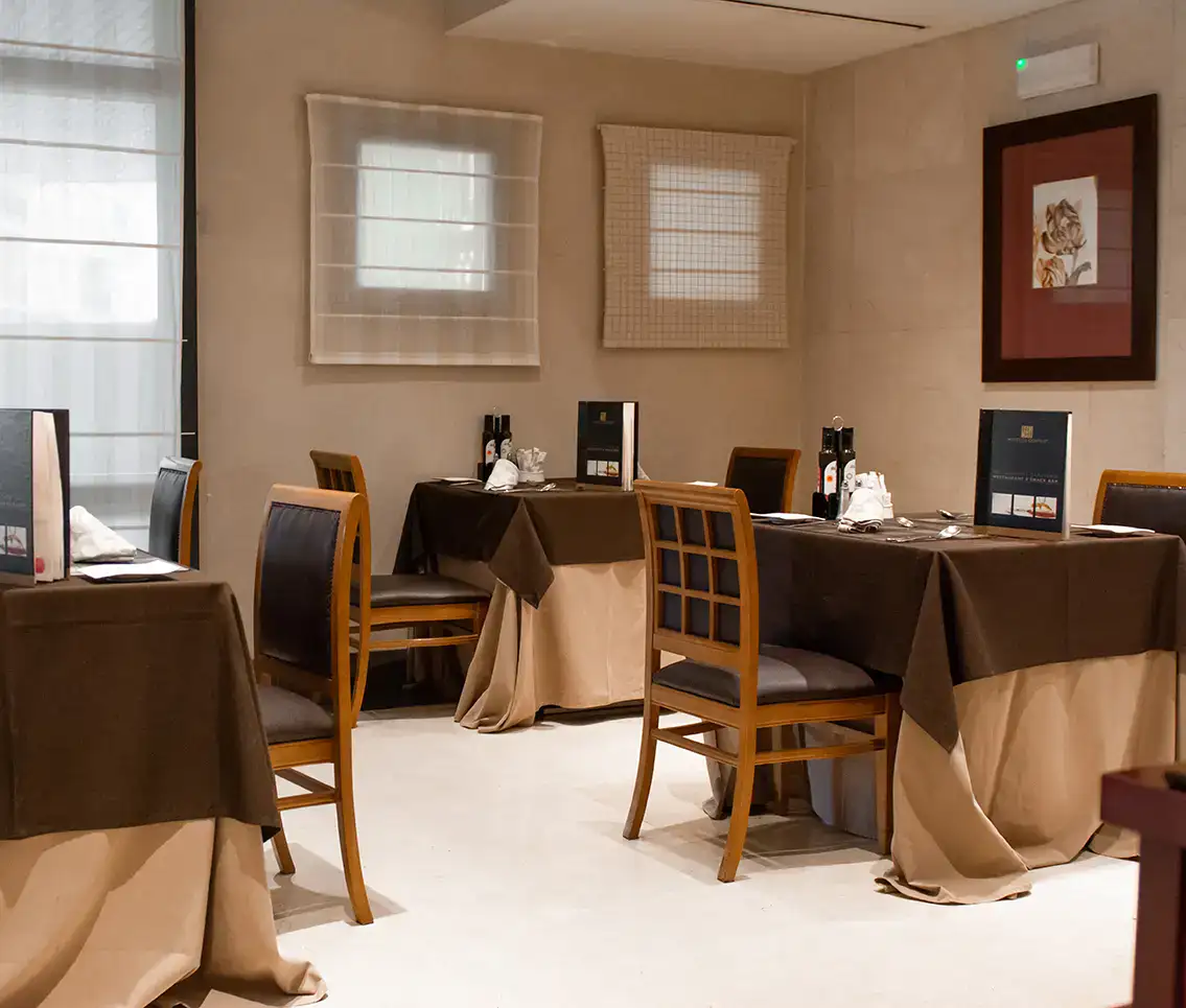 Restaurante acogedor con mesas elegantes, sillas de madera y luz suave.