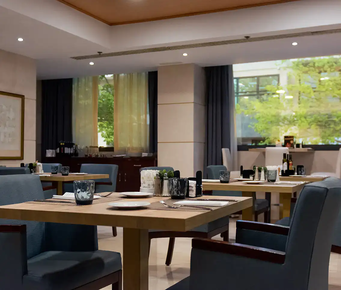 Restaurante elegante con mesas dispuestas, decoraci&oacute;n moderna y luz natural.