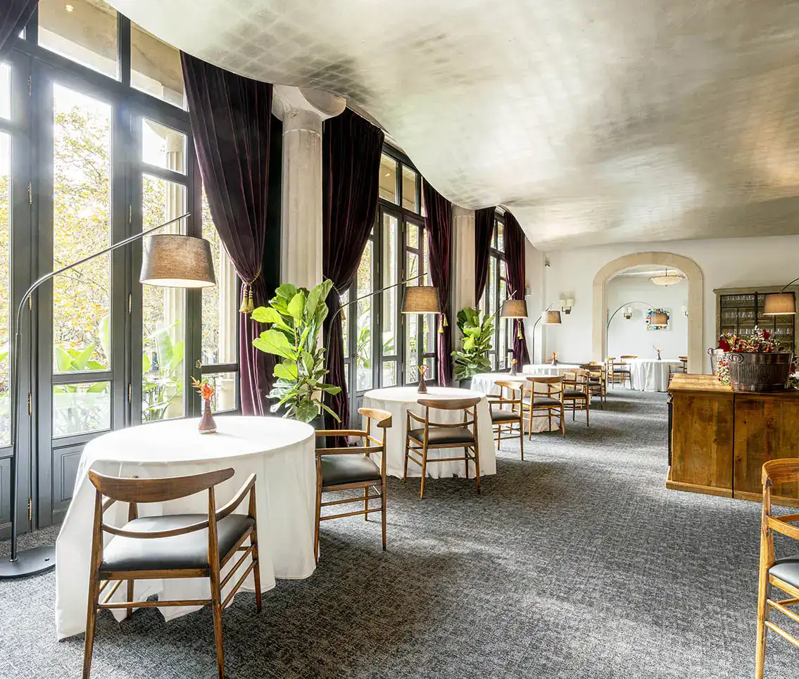 Sala de comedor elegante con mesas redondas, sillas y l&aacute;mparas de pie modernas.