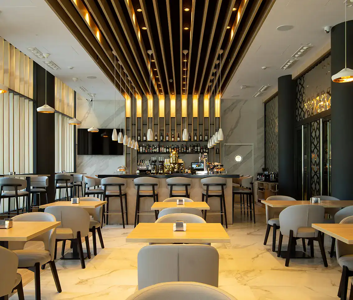 Restaurante moderno con mesas de madera y barra iluminada.