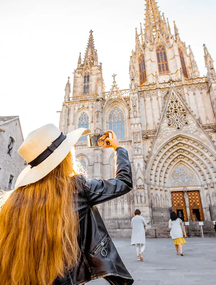 Mujer toma foto de una catedral g&oacute;tica con su celular en una plaza.