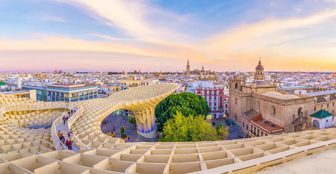 Vista panor&aacute;mica de un edificio moderno en una ciudad con cielo al atardecer.