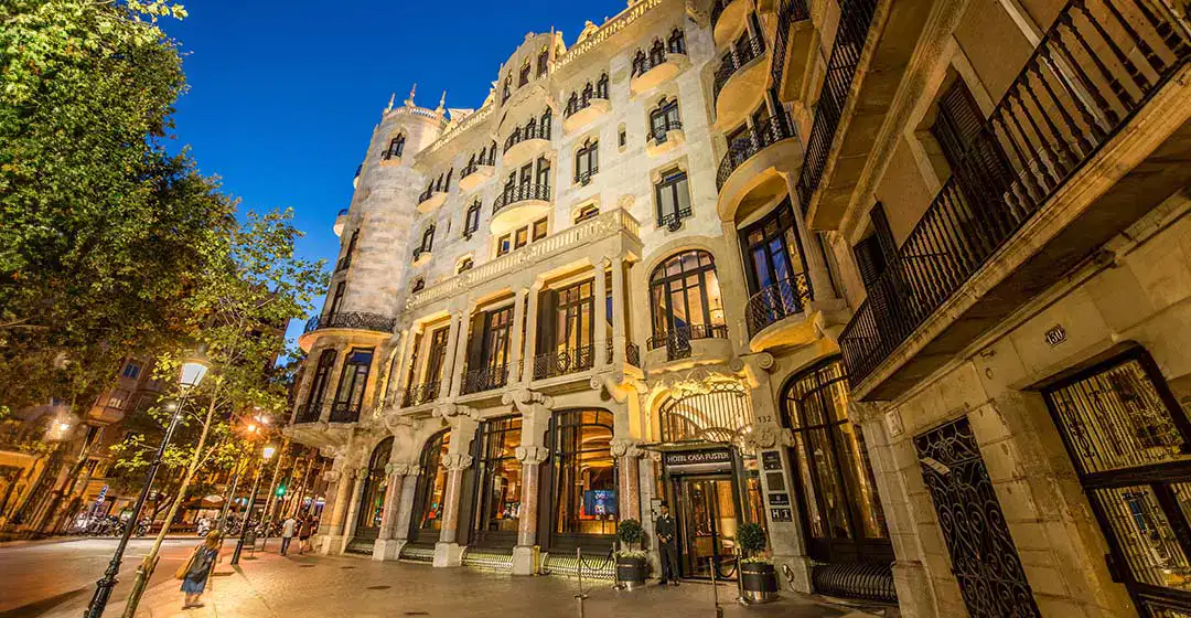 Edificio iluminado de noche con arquitectura cl&aacute;sica y balcones decorativos.