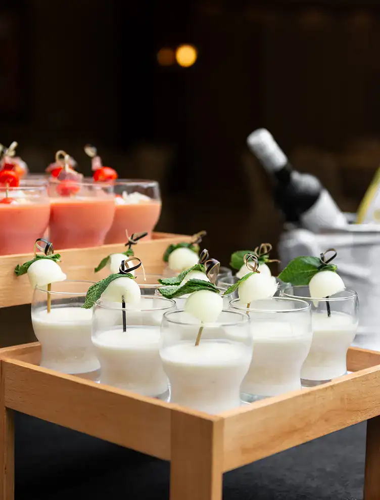 Copas de bebidas blancas y rosadas adornadas con frutas y hojas de menta.