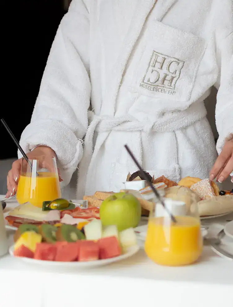 Desayuno con frutas, panes y jugo en habitaci&oacute;n de hotel.