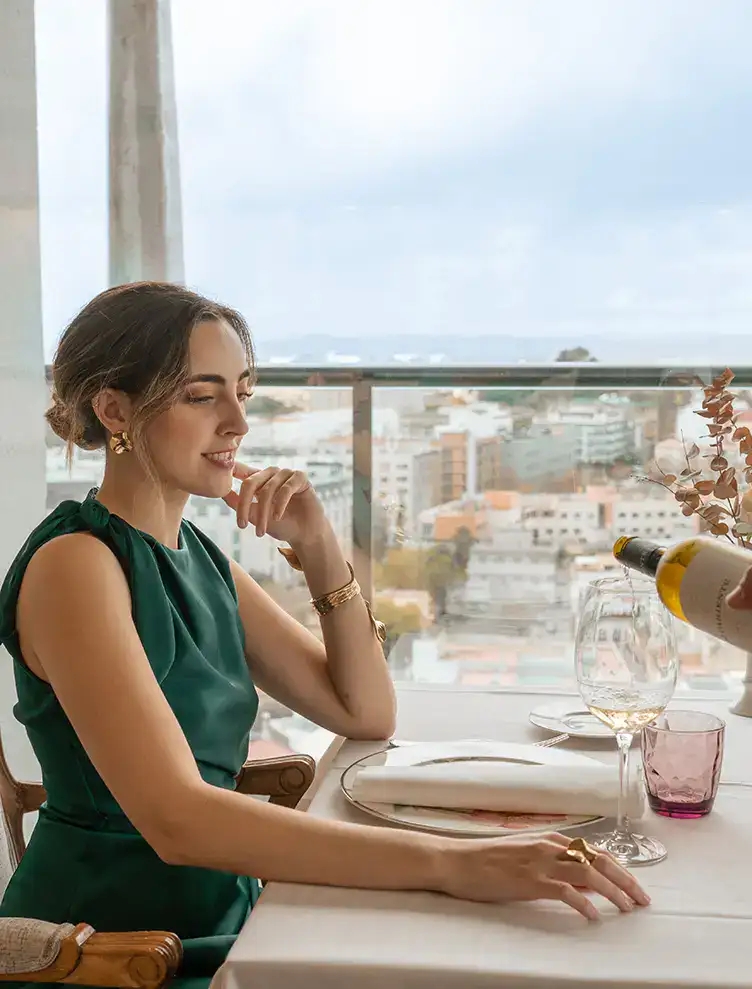 Mujer sentada en un restaurante observando mientras le sirven vino.