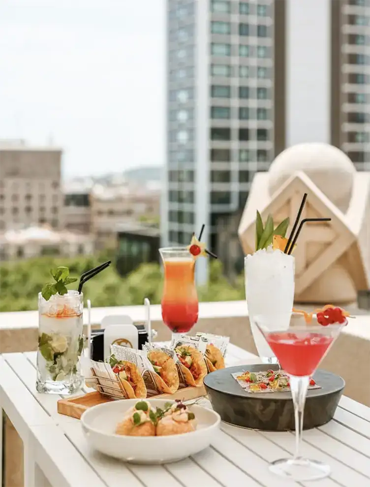 Mesa con c&oacute;cteles y bocadillos en una terraza urbana.