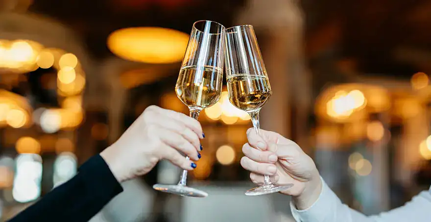 Dos personas chocan copas de champagne en un brindis.