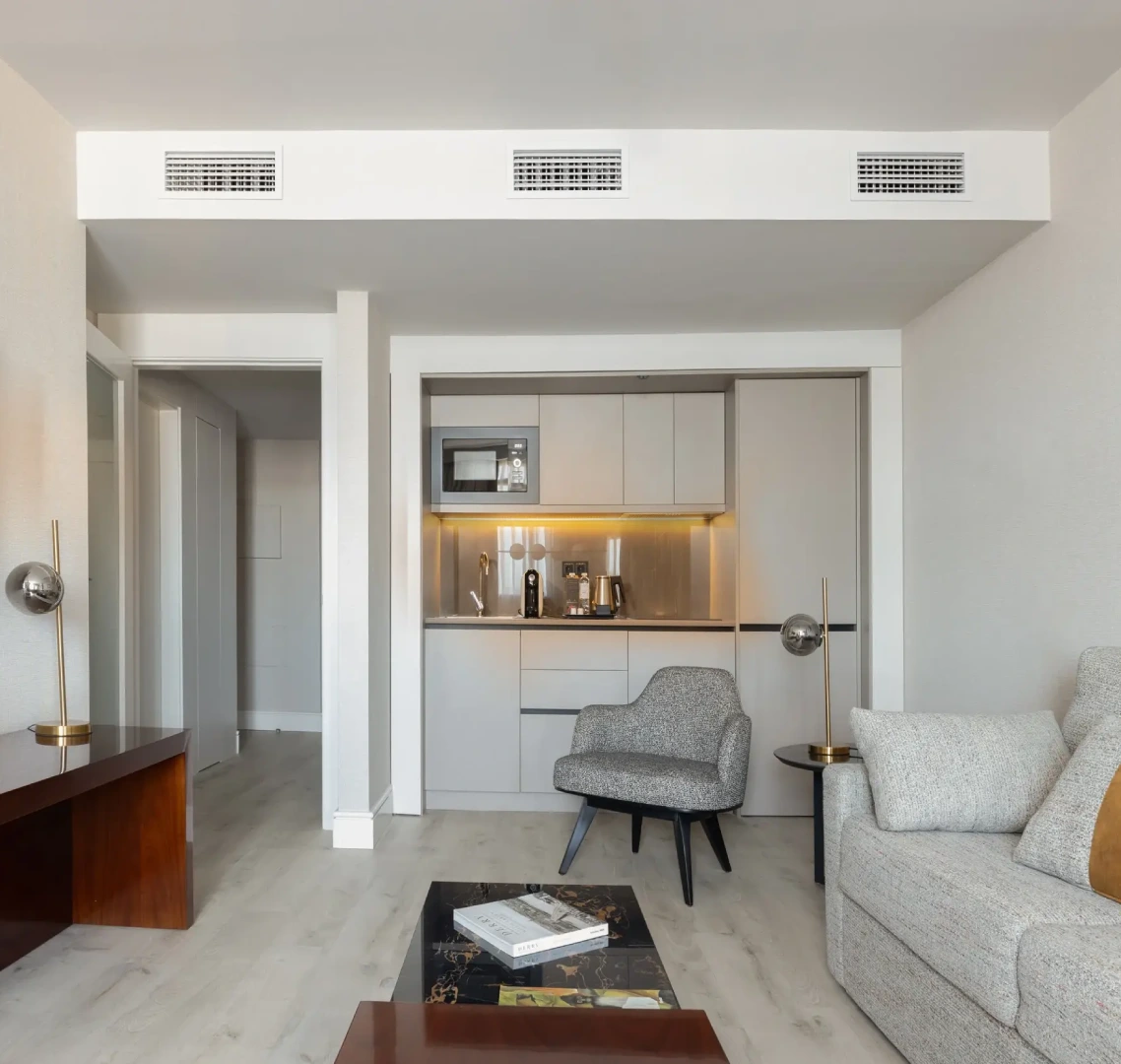 Sala moderna con cocina integrada, sof&aacute;, y mesa de centro.