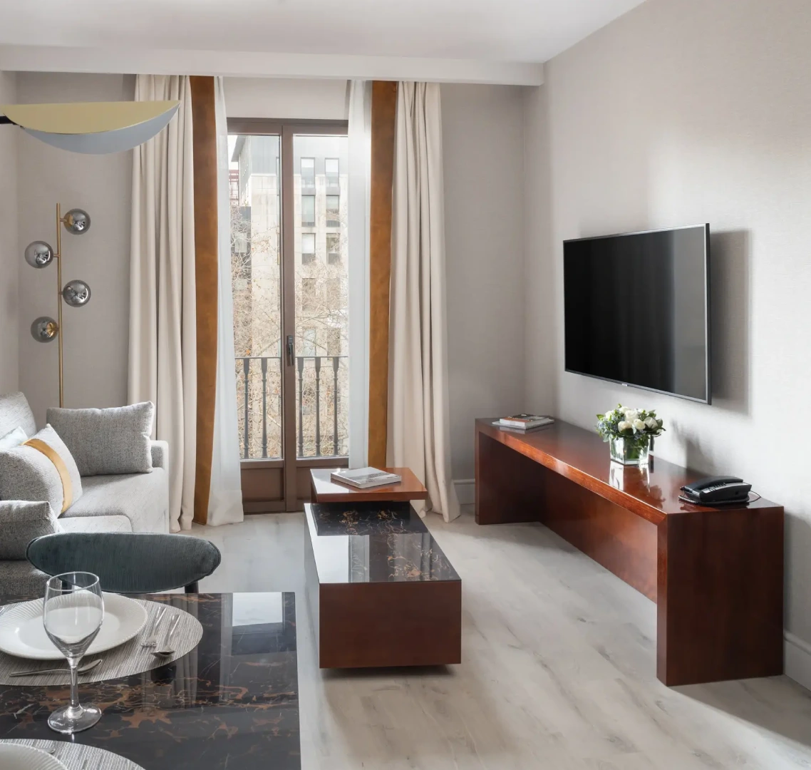 Sala moderna con muebles de madera, sof&aacute; gris y televisor.