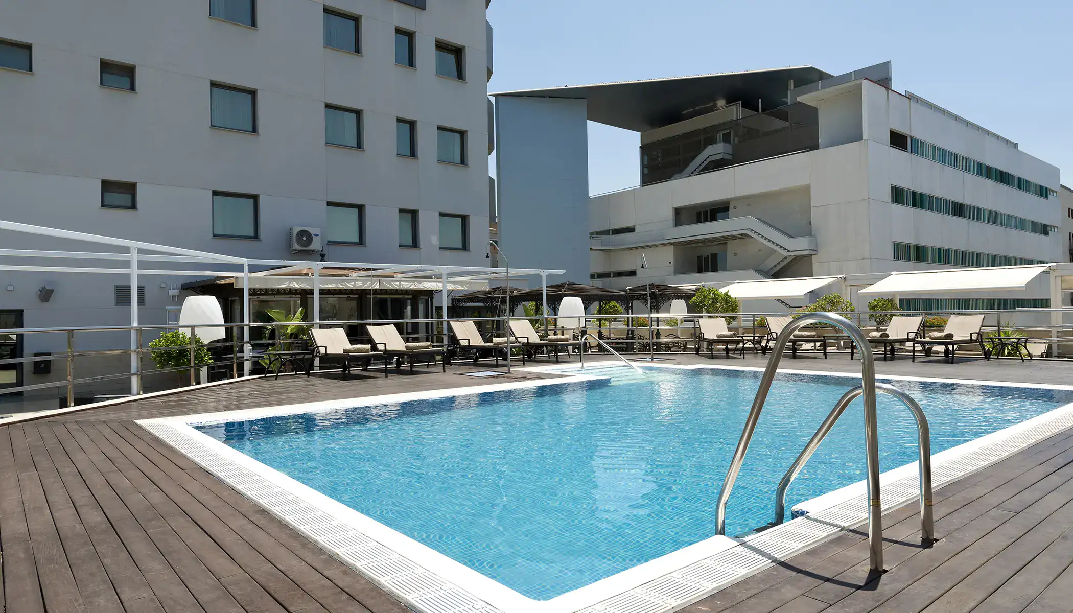 Piscina al aire libre con tumbonas en un hotel moderno.