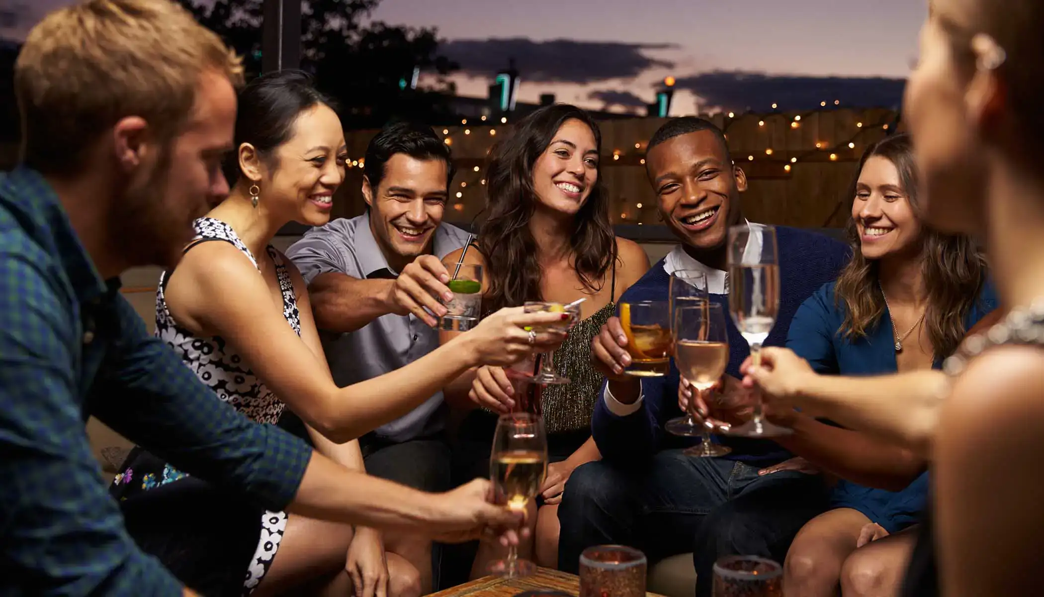 Grupo de amigos brindando al aire libre al atardecer.