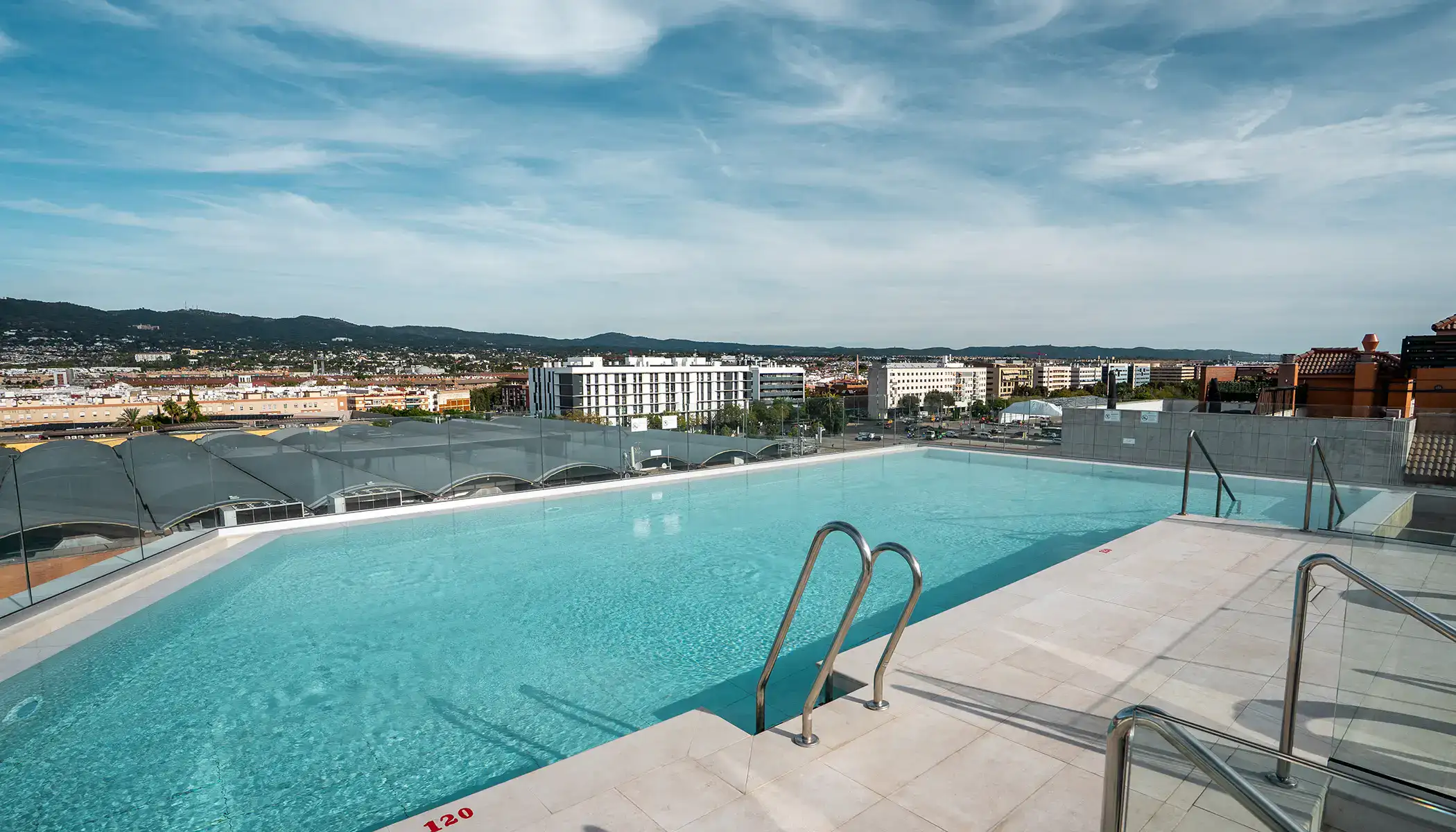 Piscina en la azotea con vista a la ciudad y monta&ntilde;as al fondo.