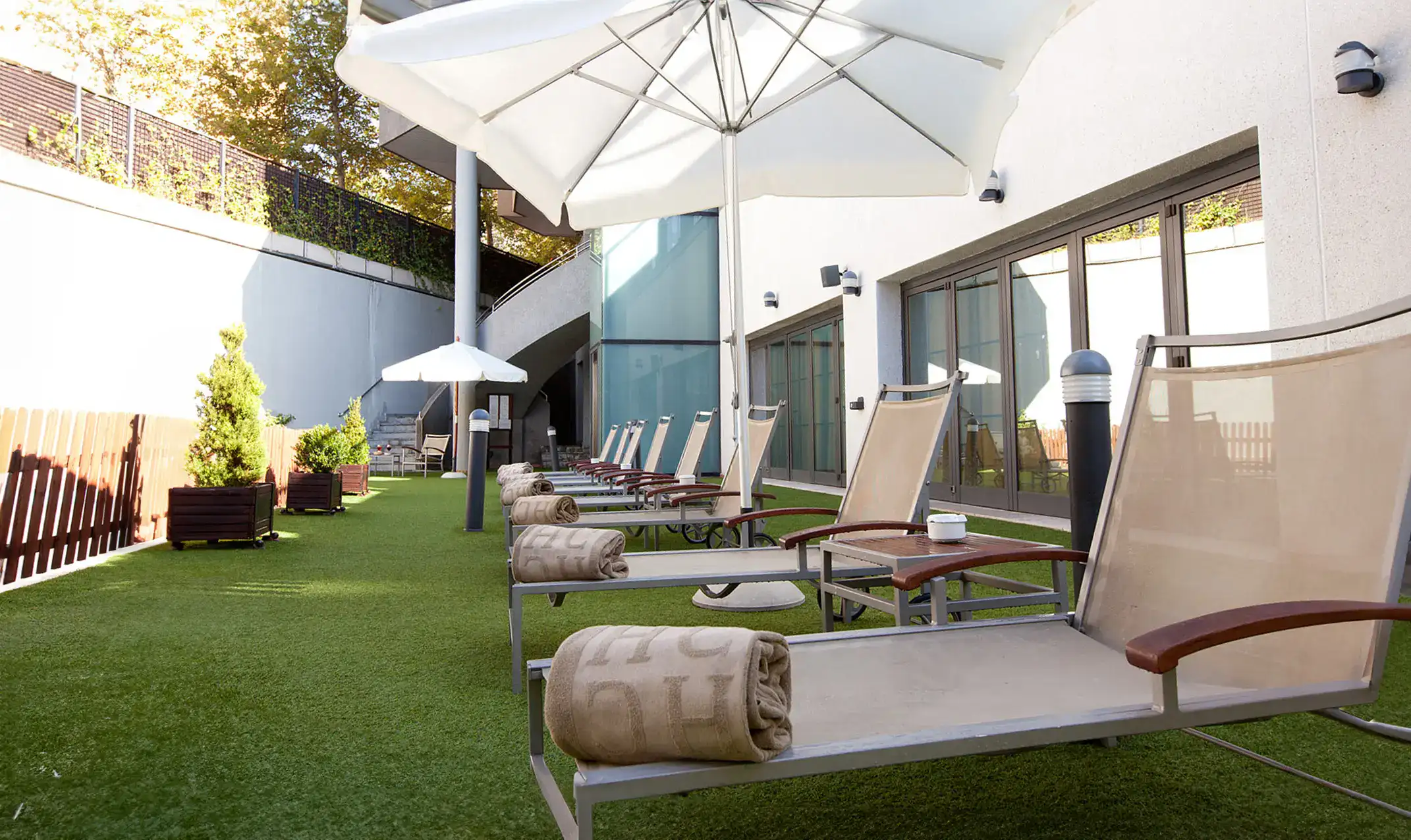 Sillas reclinables con toallas bajo sombrillas al aire libre.