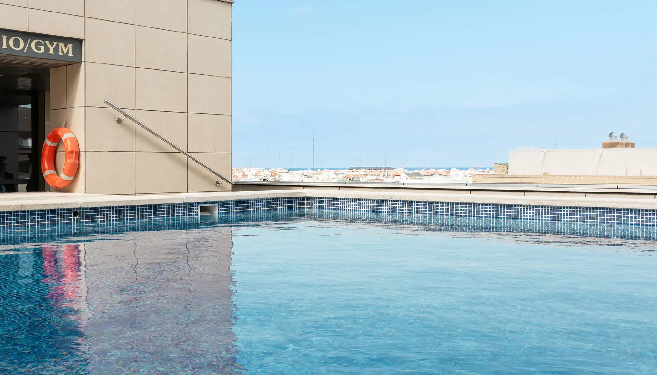 Piscina en la azotea con salvavidas al lado de un gimnasio.