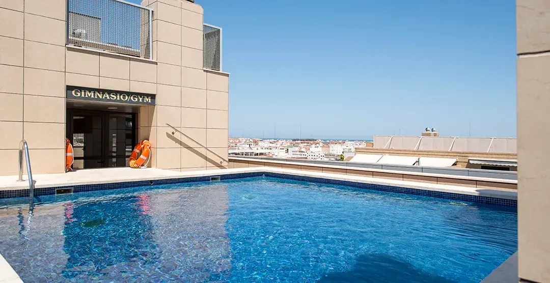 Piscina en la azotea junto al gimnasio con vista a la ciudad.