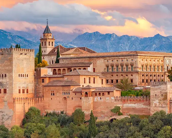 La Alhambra al atardecer con monta&ntilde;as al fondo.