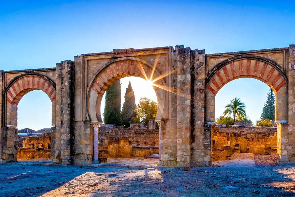 Arcos hist&oacute;ricos al amanecer con el sol brillando a trav&eacute;s de ellos.