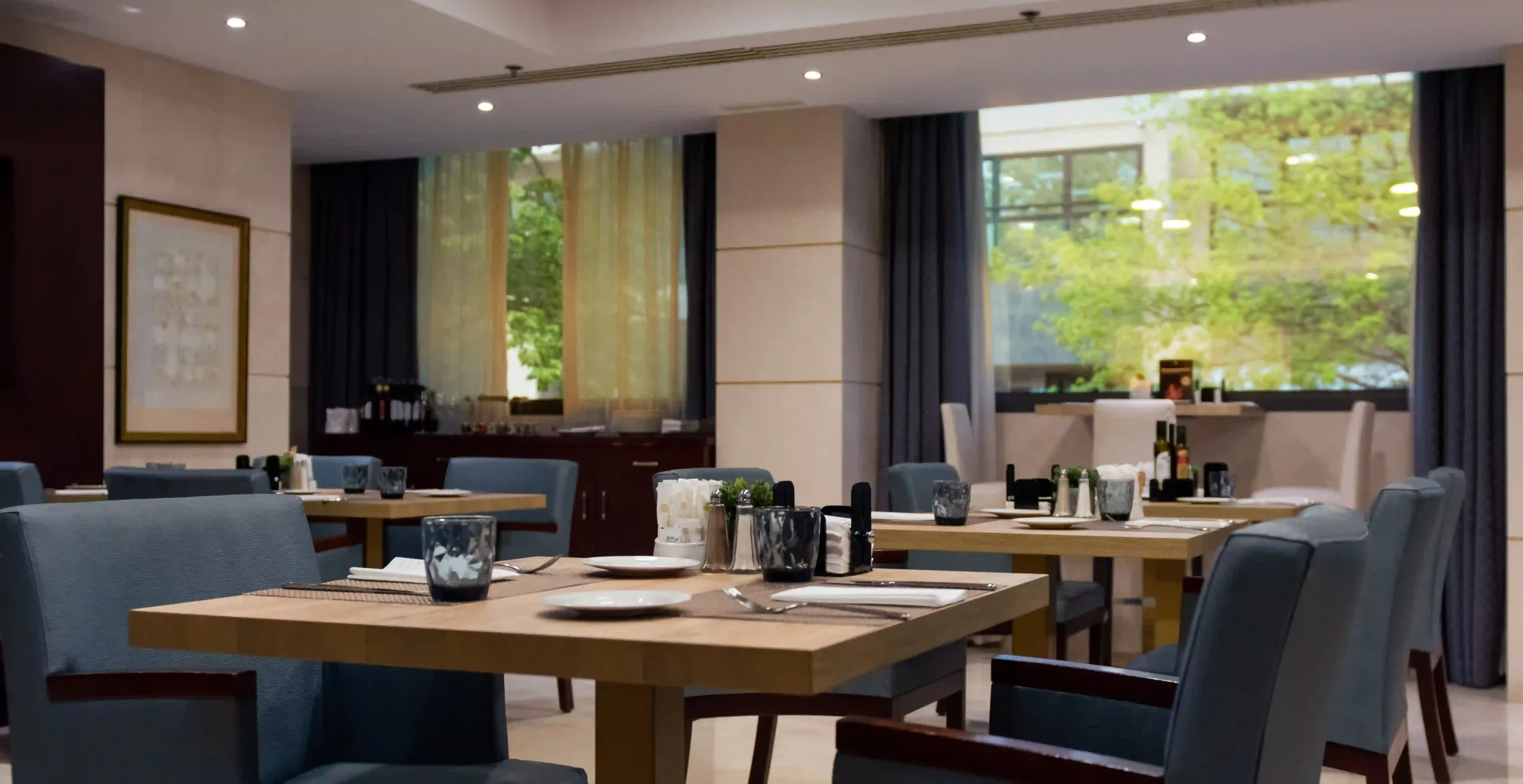 Restaurante elegante con mesas preparadas y sillas azules.