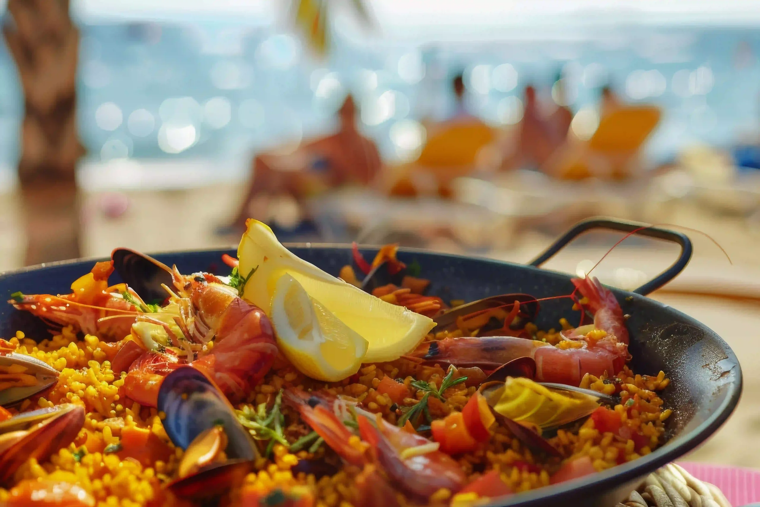 Paella de mariscos con lim&oacute;n en la playa.