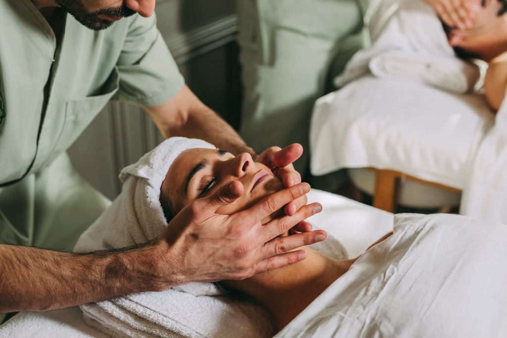 Person receiving a relaxing face massage while covered with a towel.