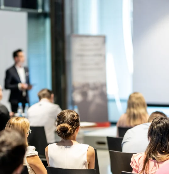 Personas en conferencia, prestando atenci&oacute;n al orador al frente. Ambiente profesional.