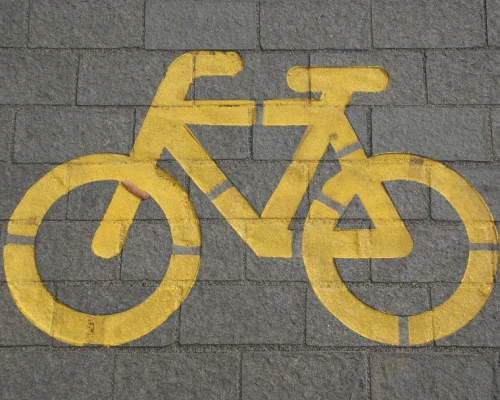 S&iacute;mbolo amarillo de bicicleta pintado en el suelo de adoquines grises.