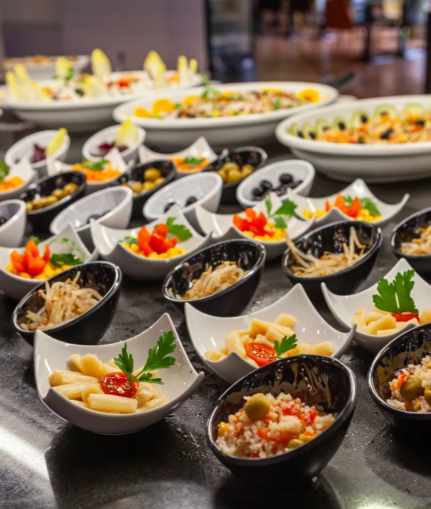 Cuencos con variedad de ensaladas y aperitivos, decorados con hierbas y servidos en una mesa.