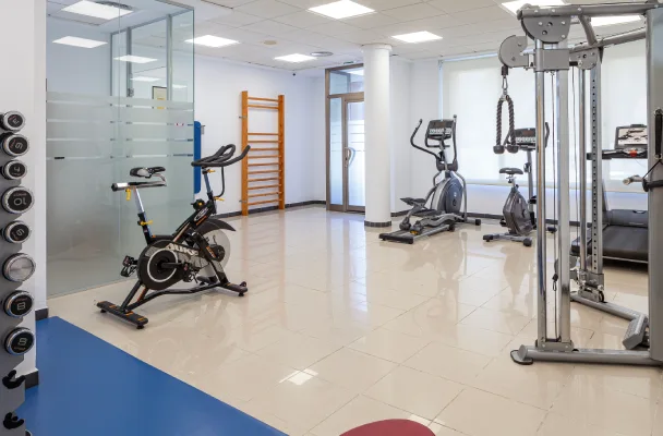 Gimnasio moderno con bicicletas est&aacute;ticas, el&iacute;pticas y equipo de entrenamiento de pesas.