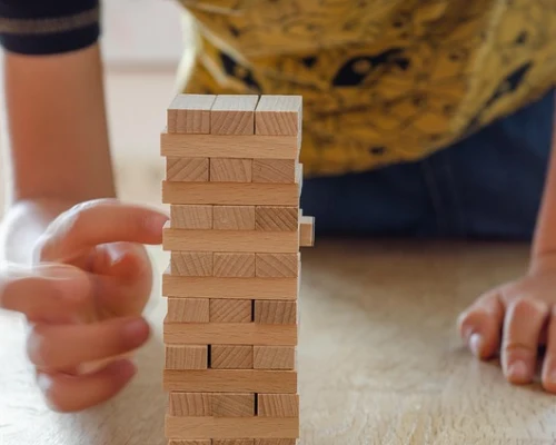 Persona jugando Jenga, retirando cuidadosamente una pieza de madera.