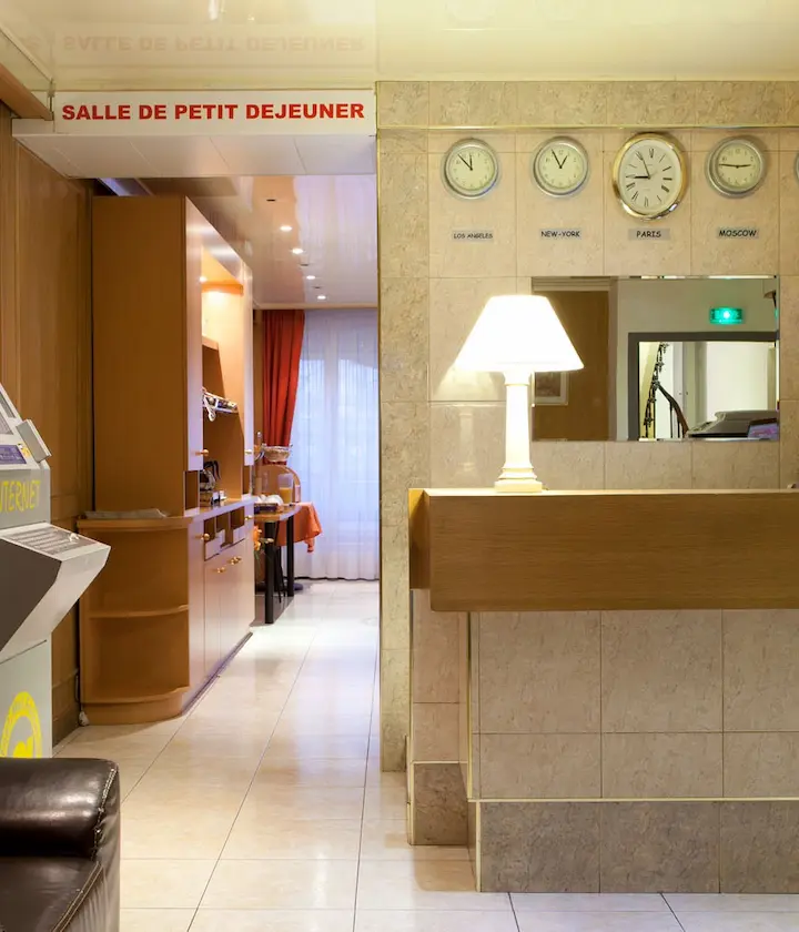 Hall d'hôtel avec horloges mondiales et accès à la salle de petit déjeuner.