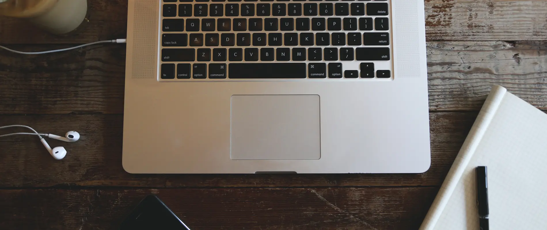 Clavier d'ordinateur portable sur bureau en bois avec écouteurs et cahier.