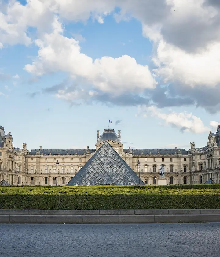 Pyramide du Louvre avec ciel partiellement nuageux en arrière-plan.