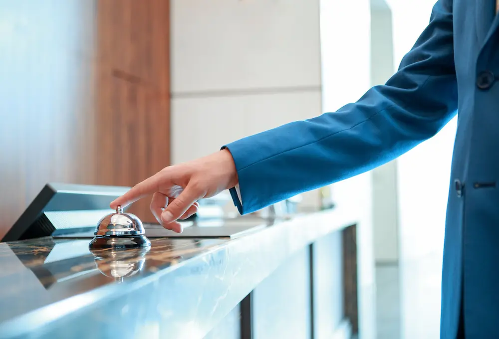 Doigt appuyant sur une sonnette d'hôtel à la réception.