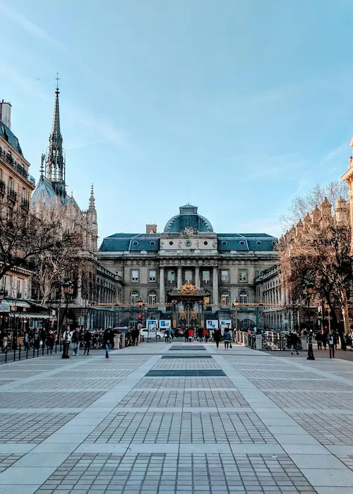 Un bâtiment historique avec une cour pavée et de nombreuses personnes autour.