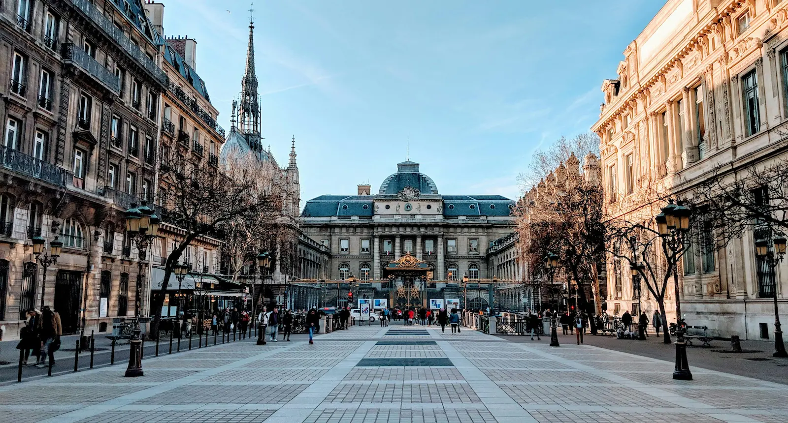 Une place bordée de bâtiments historiques et d'une église sous un ciel bleu.