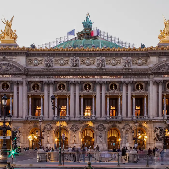 Façade d'un opéra historique avec détails architecturaux et statues dorées.