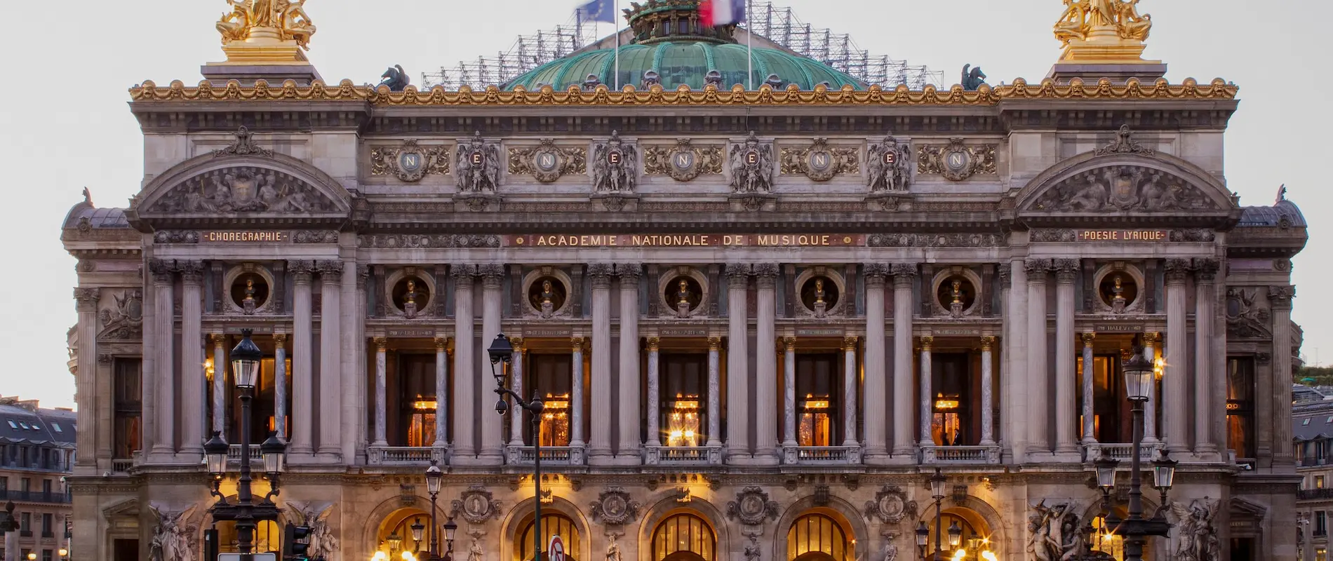 Façade du Palais Garnier à Paris, illuminée, avec des détails architecturaux ornés.