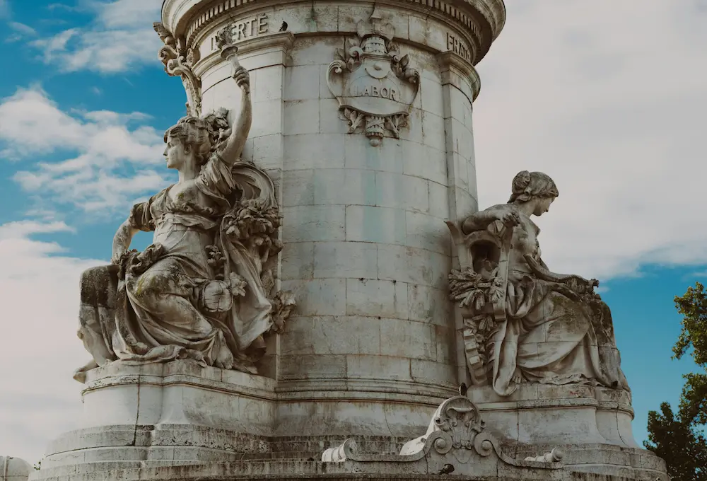 Statues en pierre ornant un monument, ciel bleu en arrière-plan.
